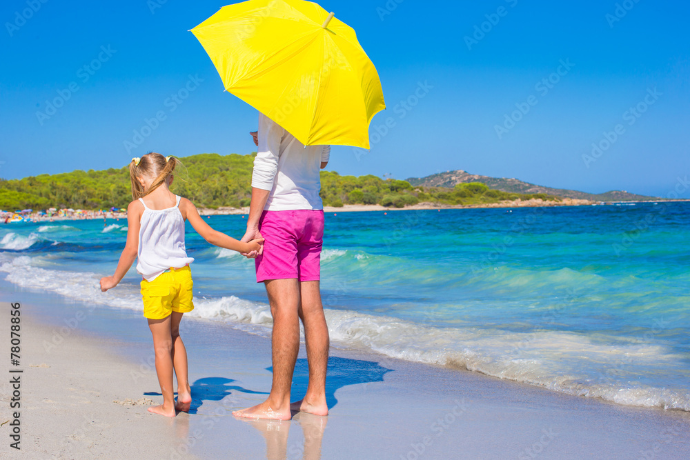 Little girl and young dad at white beach with yellow umbrella