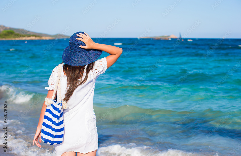 Young woman with straw hat and blue stripy bag at tropical beach