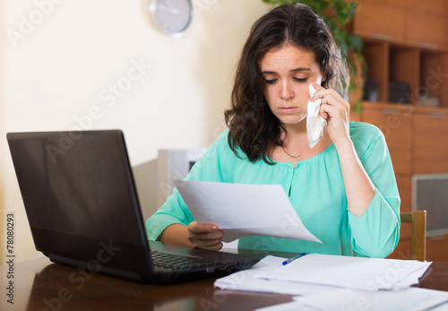 Sad woman with documents and laptop