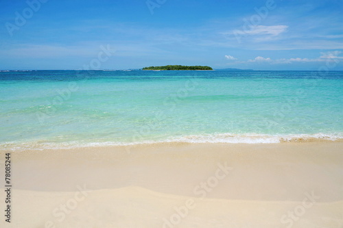 Beach sand with tropical island at the horizon