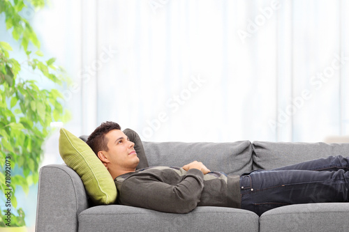 Relaxed young man lying on a sofa at home