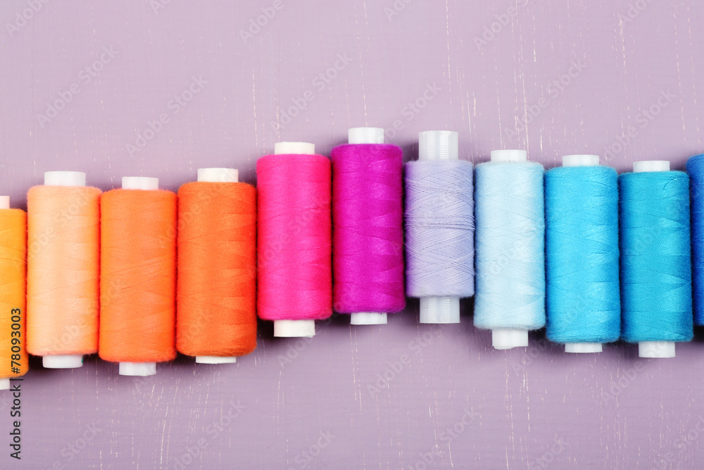 Multicolor sewing threads on wooden background Multicolor sewing threads on wooden background