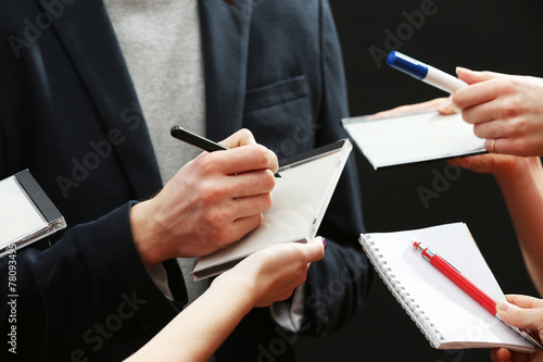 Картината върху платно Elegant man signing autograph in notebook on dark background