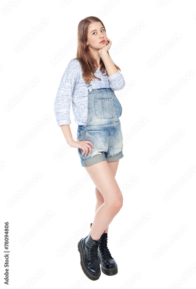 Young fashion girl in jeans overalls posing isolated