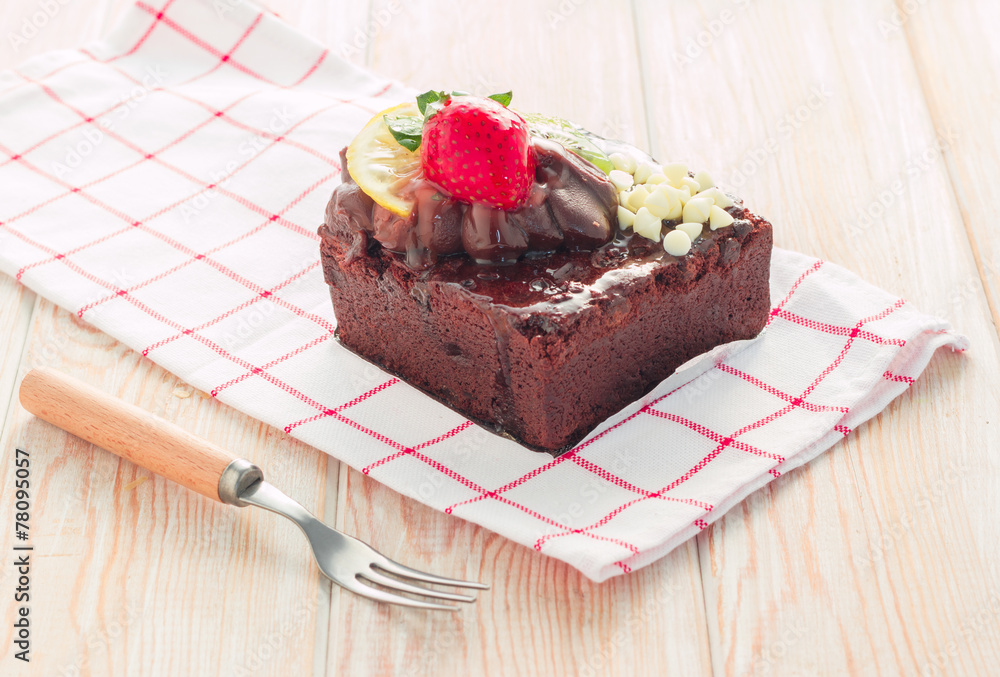 Piece of chocolate cake with icing and fresh berry on wooden bac Piece of chocolate cake with icing and fresh berry on wooden bac
