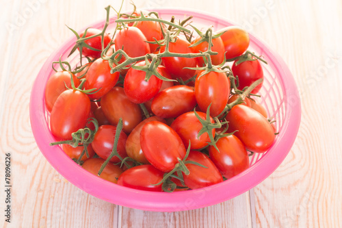 Tomatoes in a basket, on wood background.