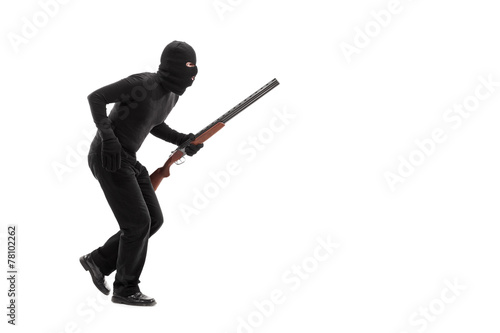 Stealthy criminal with a mask and a rifle walking