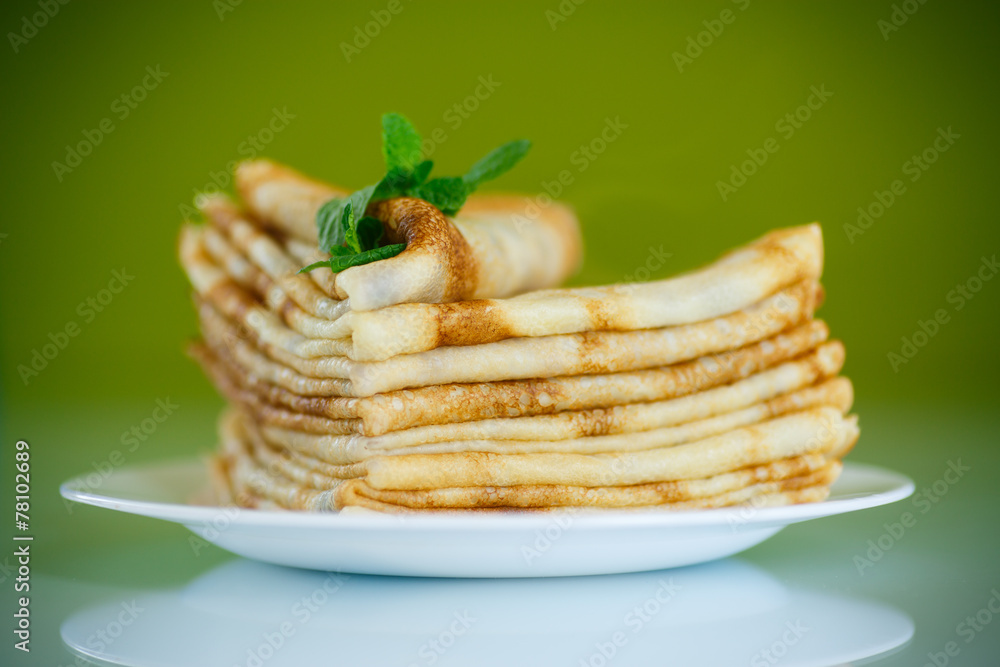 many thin pancakes on a plate many thin pancakes on a plate