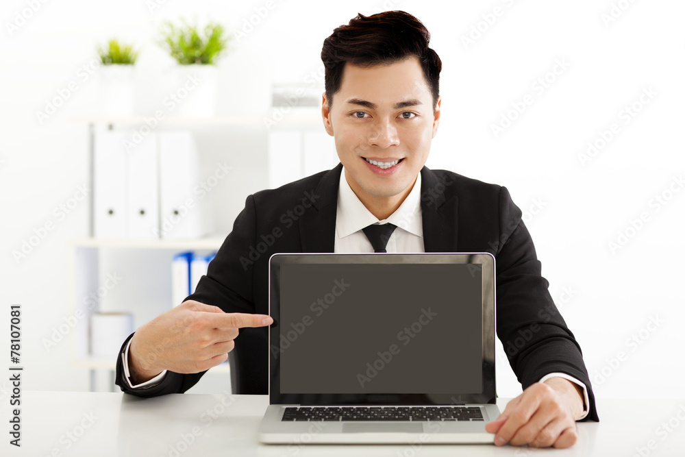 smiling young business man showing and pointing to the laptop smiling young business man showing and pointing to the laptop