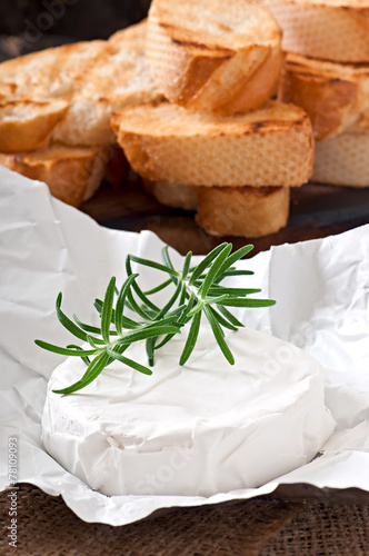 Camembert cheese and a sprig of rosemary on a wooden table