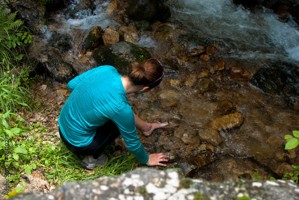 Woman washing her foot in mountain river. Woman washing her foot in mountain river.