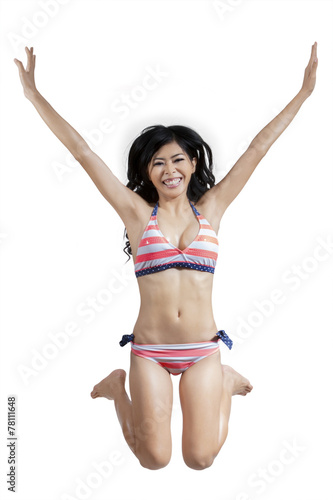 Carefree woman in bikini jumps at studio