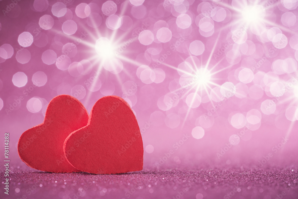 Two red hearts over abstract glitter background