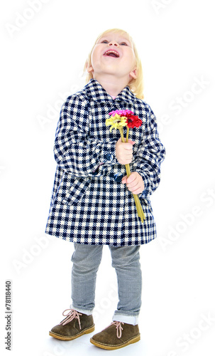 Laughing blonde little girl with a bouquet of flowers.