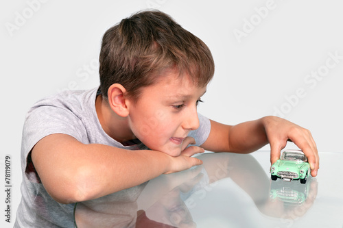 Boy playing sports retrocars on a glass table photo
