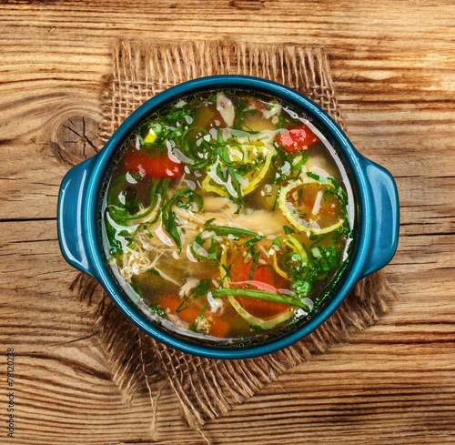 Chicken soup with vegetables on wooden table