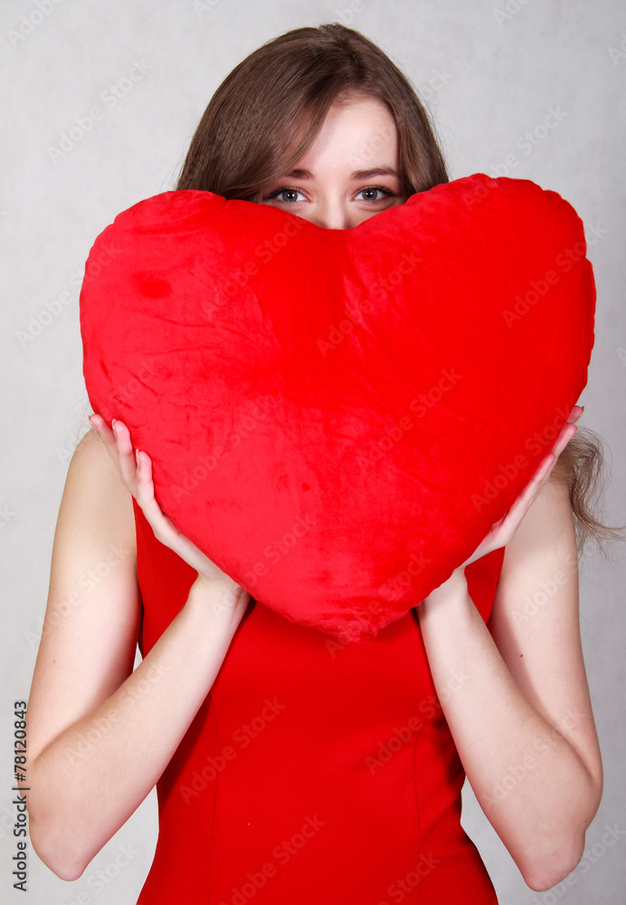 Portrait of a young attractive woman with a heart-shaped pillow Portrait of a young attractive woman with a heart-shaped pillow