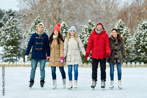 happy friends ice skating on rink outdoors