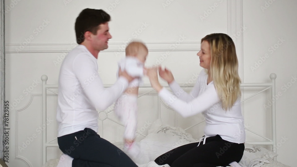 young parents playing with baby on the bed young parents playing with baby on the bed