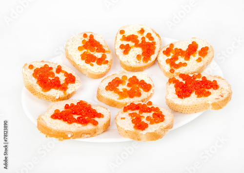 Red caviar on bread with butter on white plate closeup