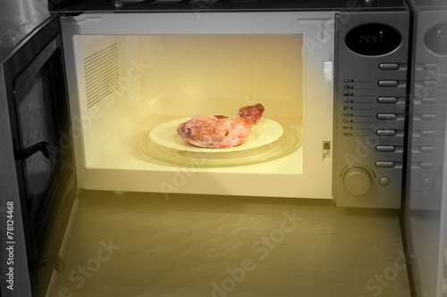 Night hunger. Heating chicken leg in microwave