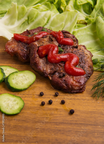 tasty grill meat with sauce and green on wooden background