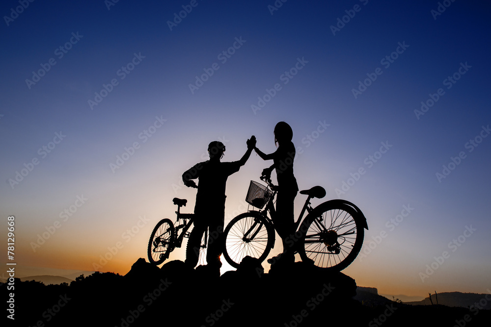 Fototapeta premium Silhouette of a man and girl on mountain bike