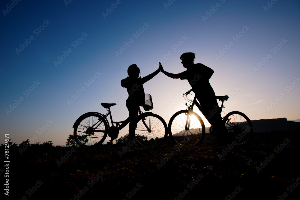 Obraz premium Silhouette of a man and girl on mountain bike