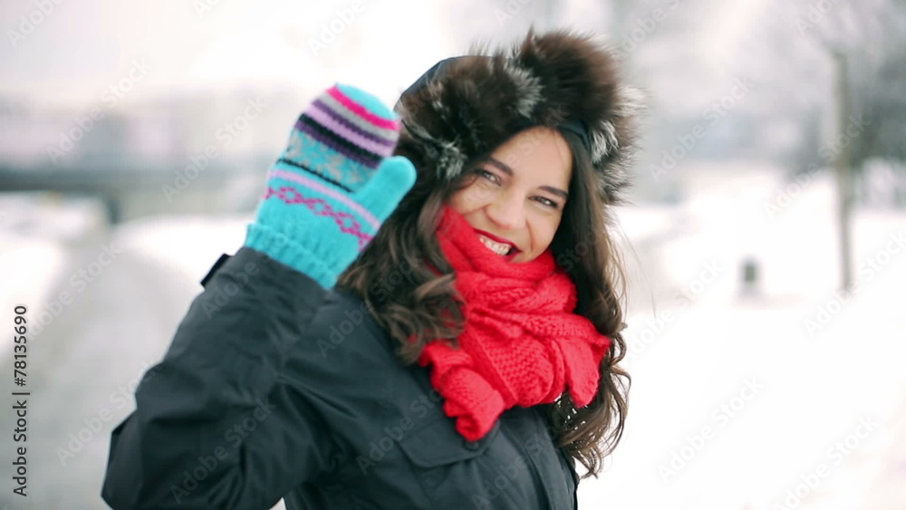 Woman walking in the snowy park and sending kiss to the camera Woman walking in the snowy park and sending kiss to the camera