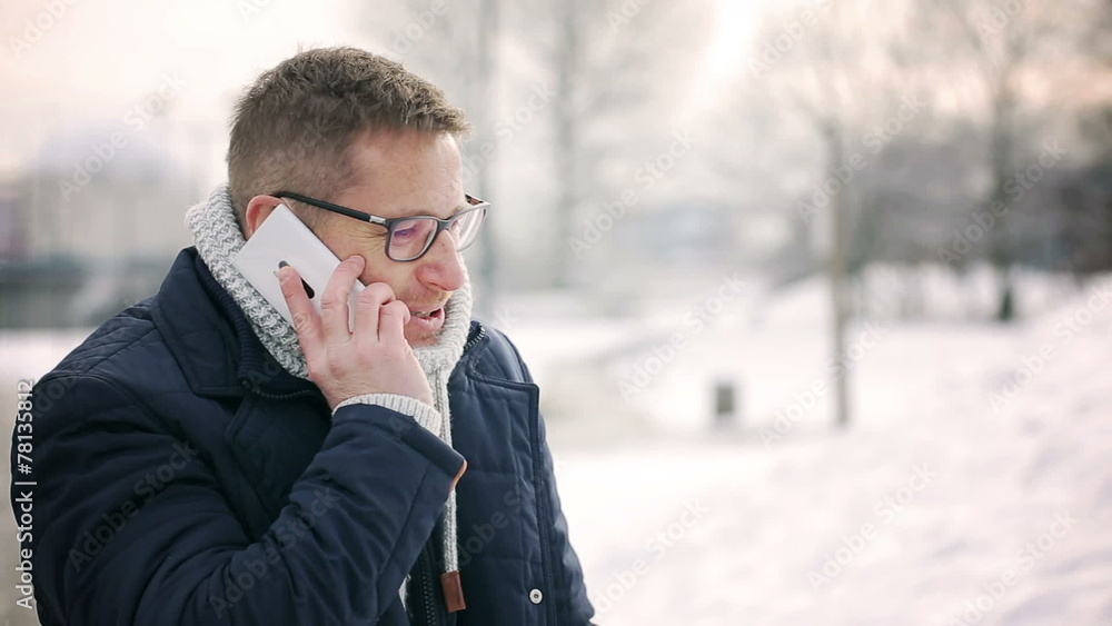 Happy man talking on cellphone in the park at winter time Happy man talking on cellphone in the park at winter time