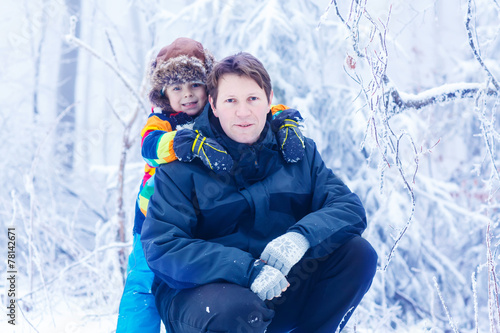 portrait of a little kid boy and his young father in in snow for