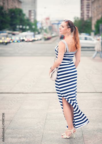 Beautiful young fashionable woman wearing striped dress in the c
