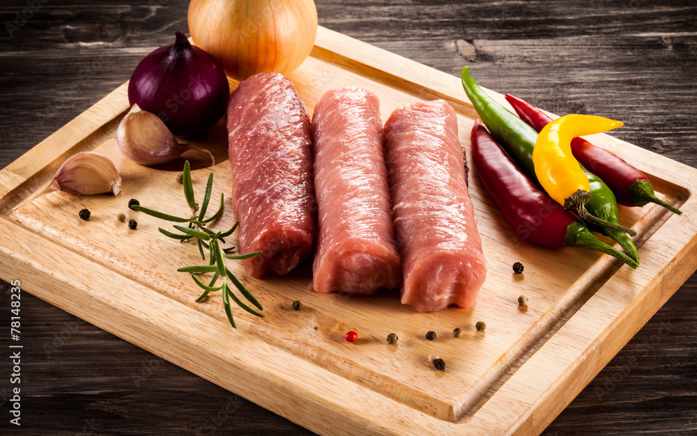 Raw pork chops on cutting board and vegetables Raw pork chops on cutting board and vegetables