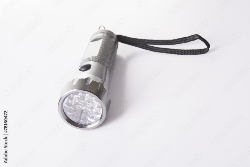A gray flashlight over a gray background on the floor A gray flashlight over a gray background on the floor