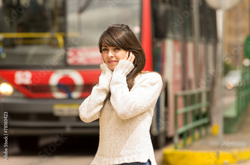 woman walking on the city street covering her ears concept of