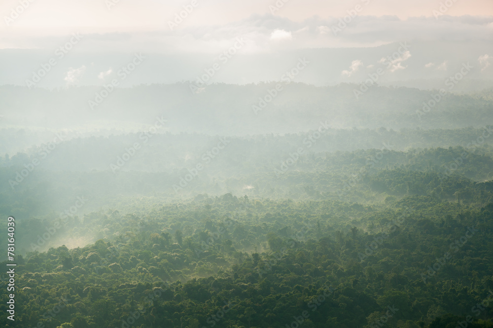 Fototapeta premium Sunlight shines through the clouds into the mountains and forest