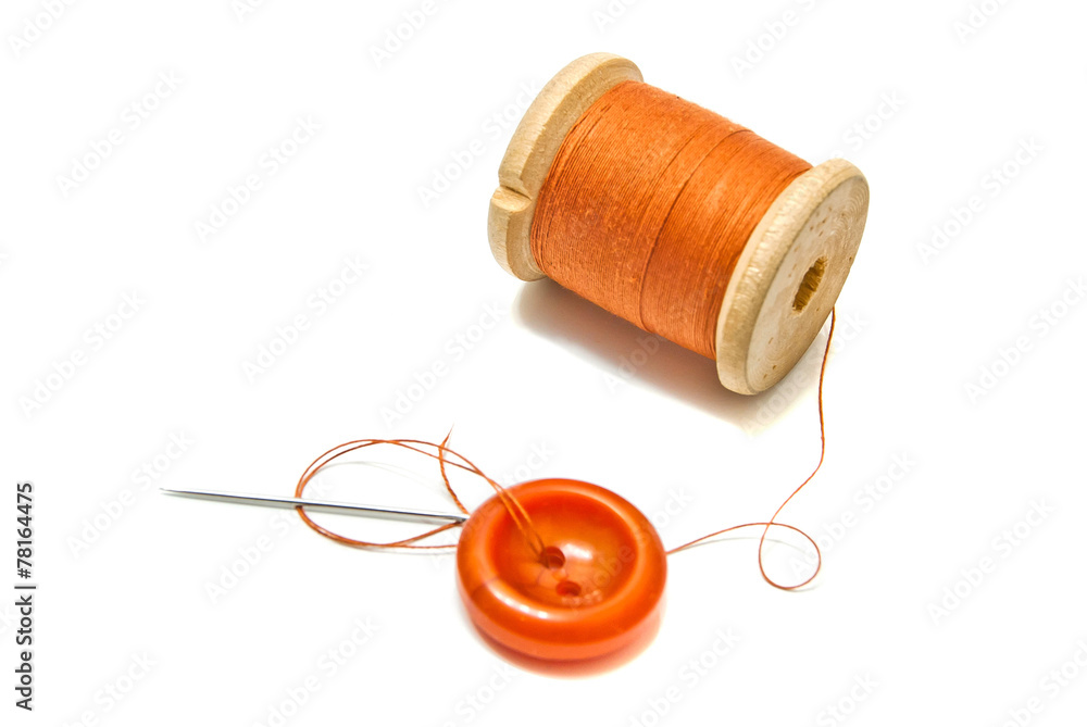 orange spool of thread, and button on white