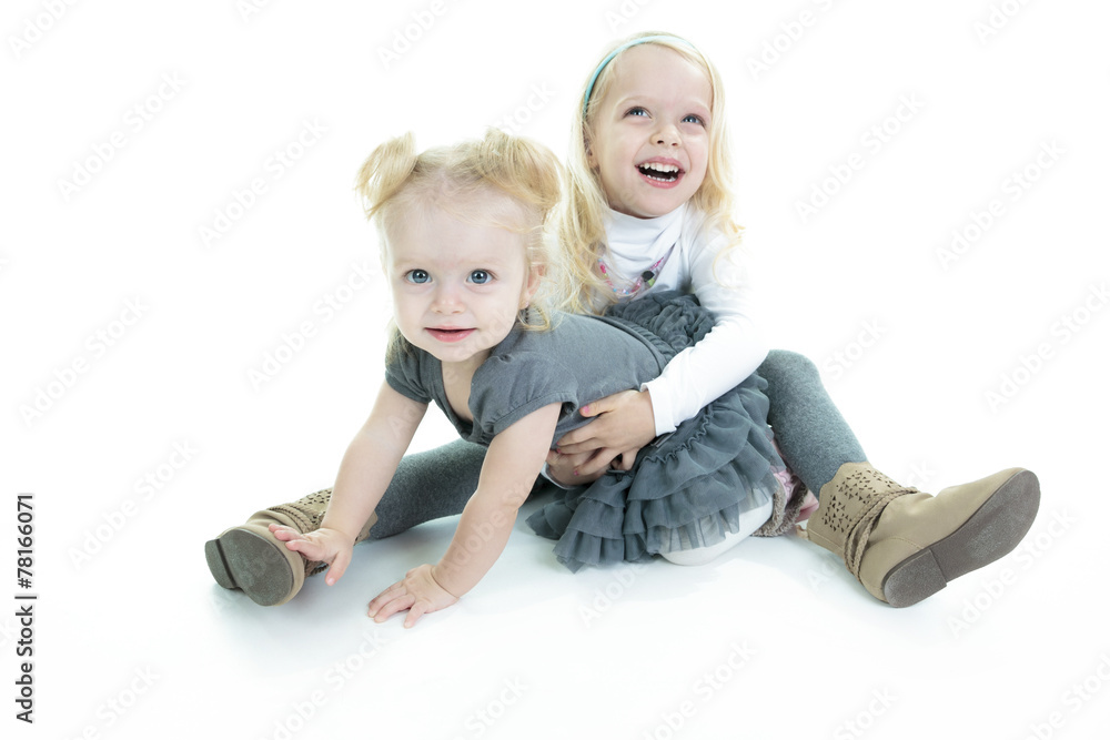 Two cute little blond sisters kneeling on the floor arm in arm c Two cute little blond sisters kneeling on the floor arm in arm c