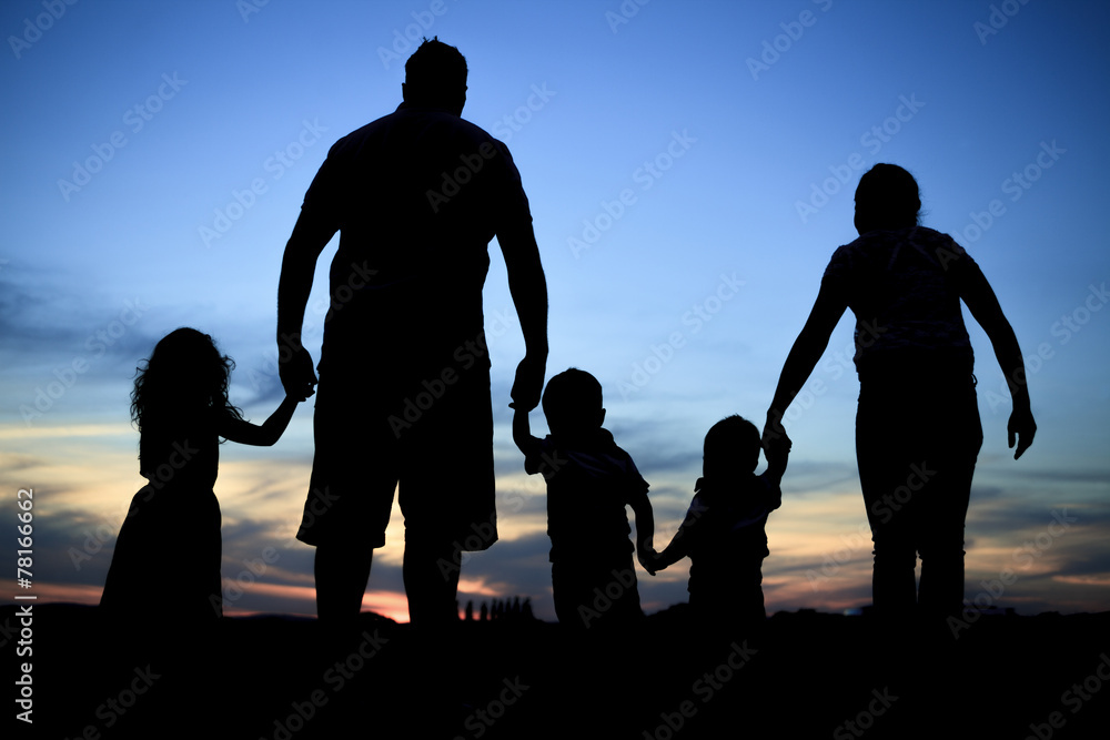 Silhouette of a young family with some childs standing