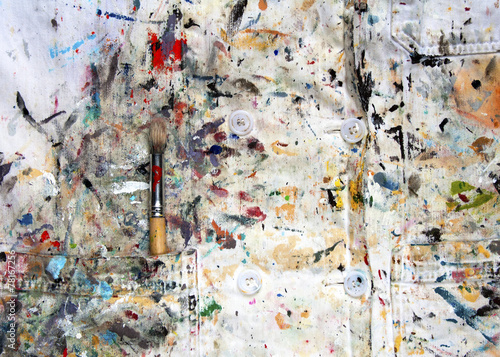 White lab coat covered in paint and one paintbrush in pocket