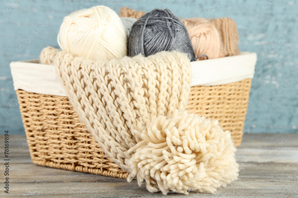 Knitting scarf and yarn in basket, on wooden background Knitting scarf and yarn in basket, on wooden background