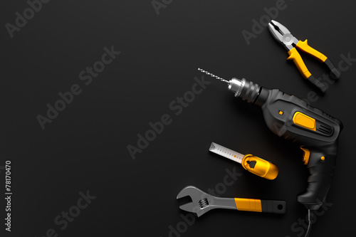 drill, wrench and construction tools on the black background tex