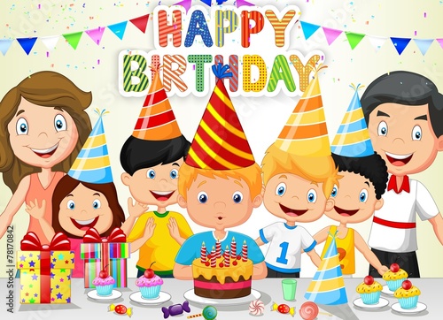 Happy boy blowing birthday candles with his family and friends