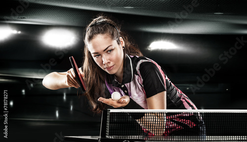 Young pretty sporty girl playing table tennis on black