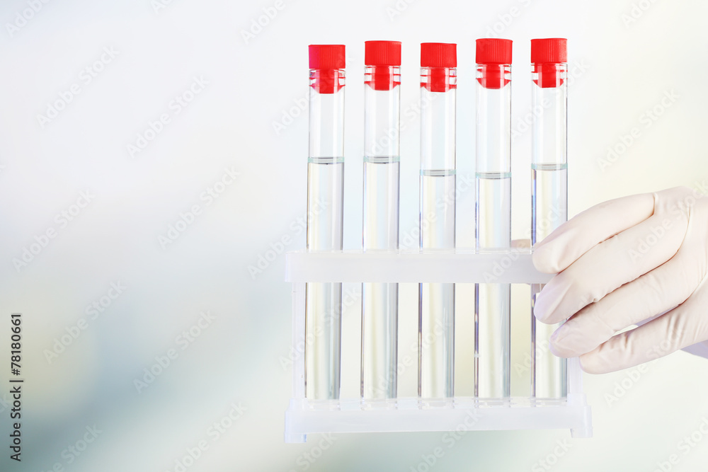 Hand holding test tubes on light background Hand holding test tubes on light background