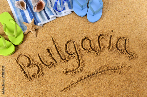 The word Bulgaria written in sand on a beach with towel flip flops seashells summer vacation holiday photo