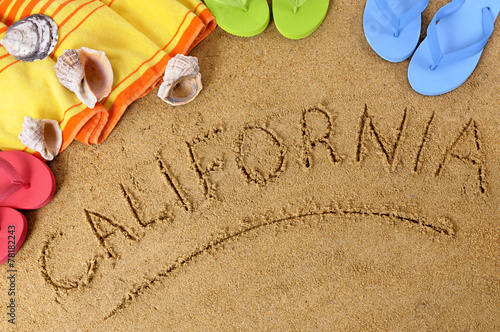The word California written in sand on a beach with towel flip flops seashells summer vacation holiday photo