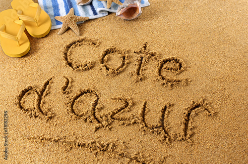 The word Cote dAzur written in sand on a beach with towel flip flops seashells France summer vacation holiday photo photo