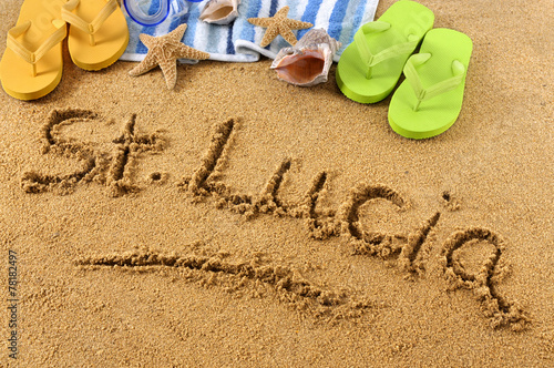 The word St Saint Lucia written in sand on a beach with towel flip flops seashells Caribbean summer vacation holiday photo