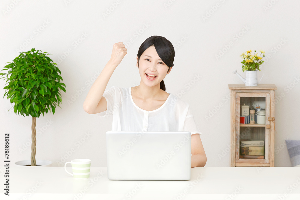 パソコンの前でガッツポーズする女性 パソコンの前でガッツポーズする女性